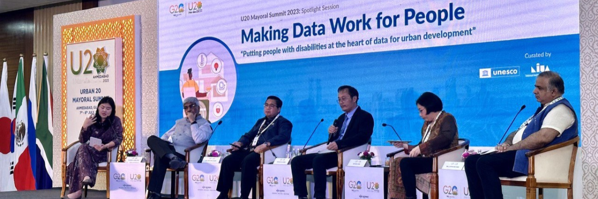 Fuad Jamil from Kota Kita on stage at the U20 Mayoral Summit in India alongside the Banjarmasin mayor and other panelists, including government officials, corporate executives, development agency leaders, and researchers.